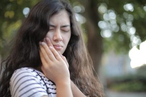 Une femme tenant sa mâchoire, exprimant de la douleur et de l'inconfort suite à une implantation basale.