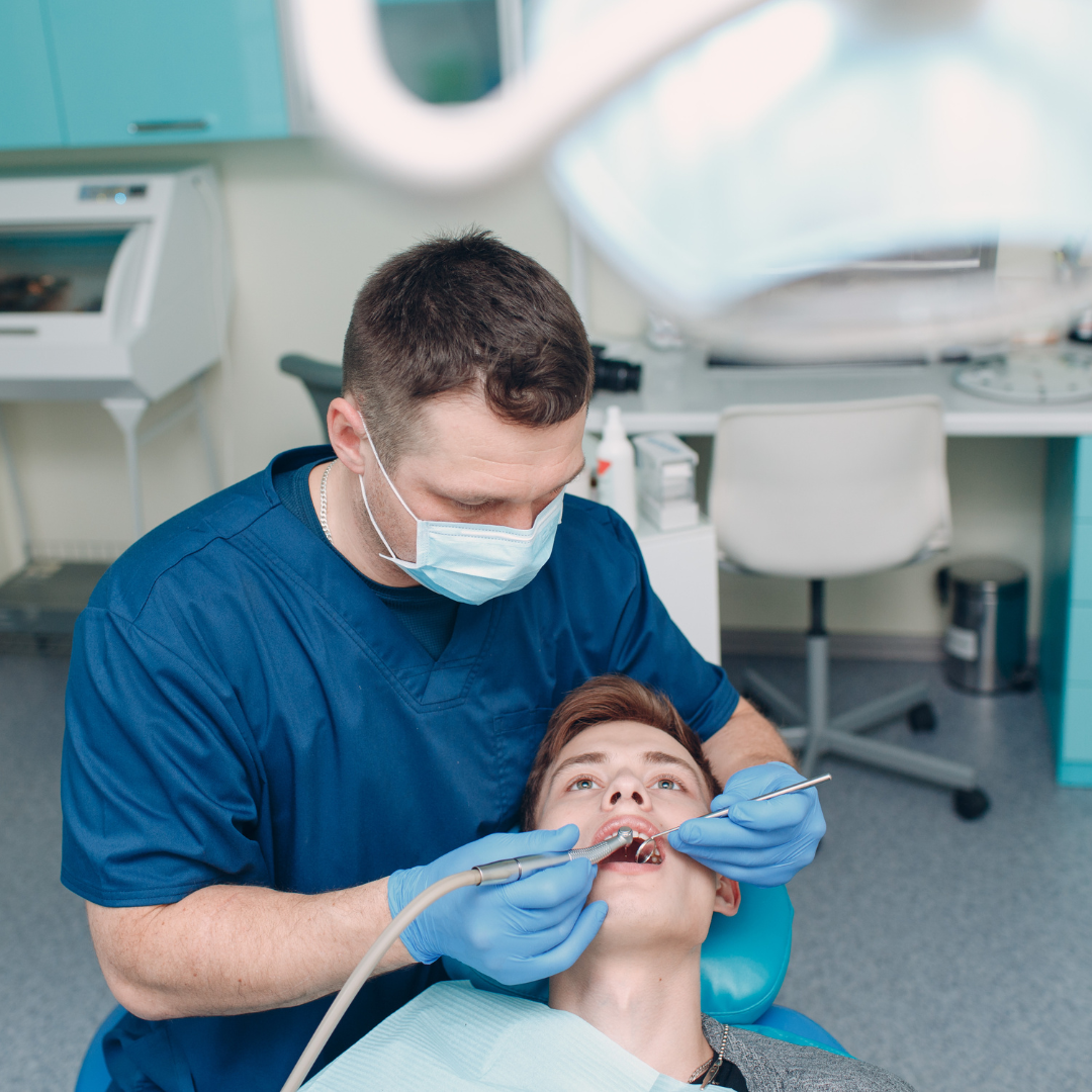 Dentiste en train de réaliser une intervention bucco-dentaire sur un patient, illustrant une étape des soins dentaires professionnels.